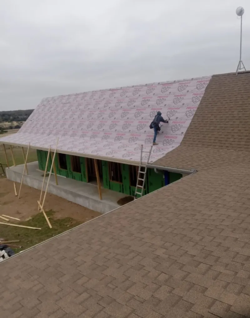 Worker preparing underlayment for a metal roof installation in Carroll